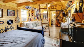 Ein rustikaler Raum mit einem Bett, Holzbalkendecke, einer Treppe und einer Wand, die mit Schallplatten dekoriert ist.
