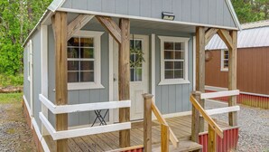 A small, single-story wooden structure with a porch, a door, and windows. - Cozy Higden Studio: Close to Greers Ferry Lake! (Higden)