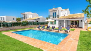 Ein Wohnhaus mit Swimmingpool, mehreren Liegestühlen und einer Terrassenanlage.