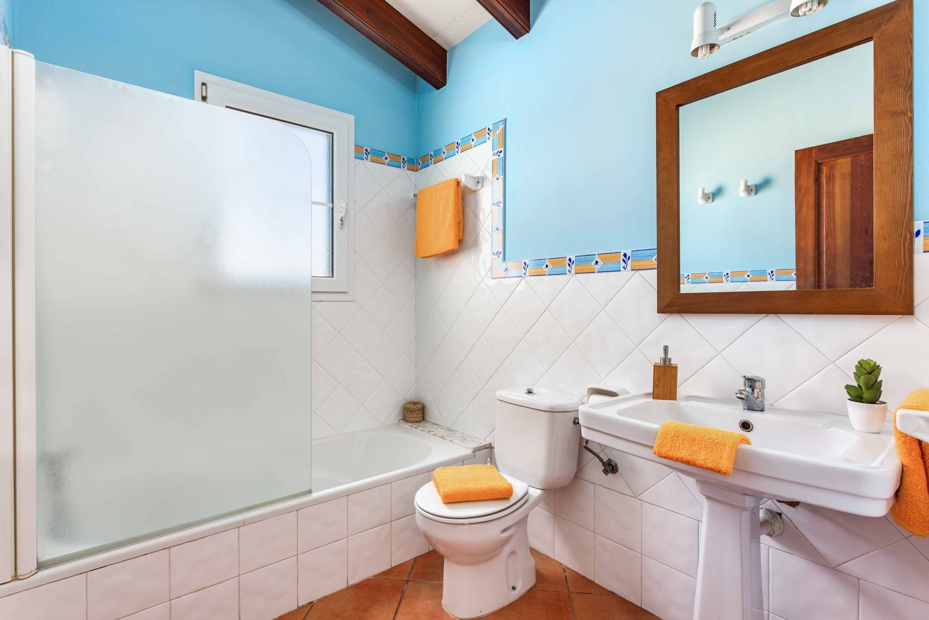 Een badkamer met bad, toilet, wastafel en spiegel.