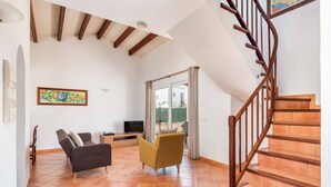 Ein Wohnzimmer mit einer Couch, einem Sessel, einem Fernseher und einer Treppe.