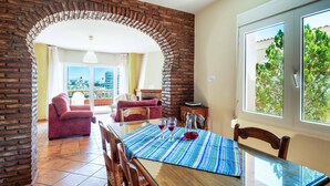 Un comedor con un arco de ladrillo, una mesa con mantel a rayas y vistas a zonas verdes al exterior.