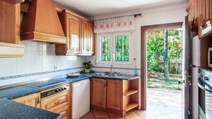 Una cocina con armarios de madera, horno empotrado y ventana con vistas al follaje.