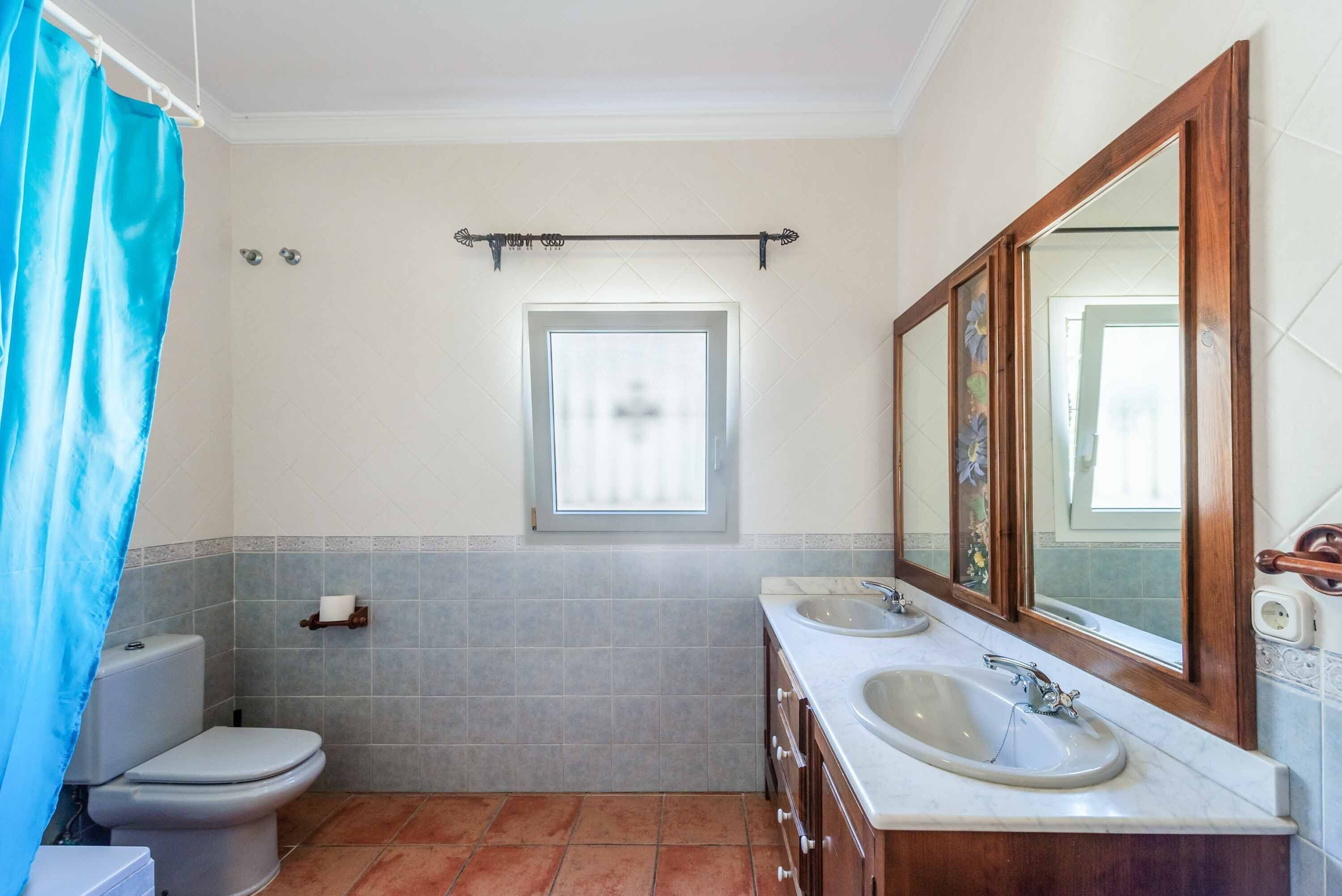 A bathroom with a toilet, two sinks, a window, and a mirror.