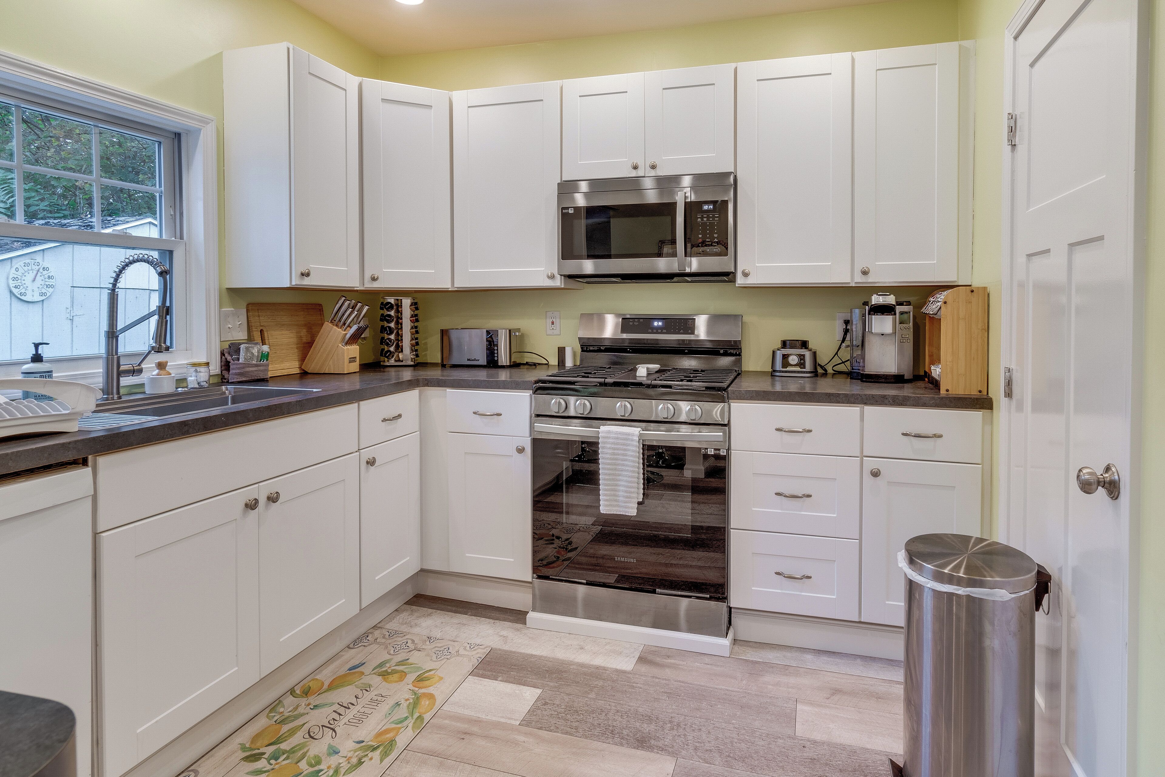 A modern kitchen with white cabinets, stainless steel appliances, and a wooden countertop.