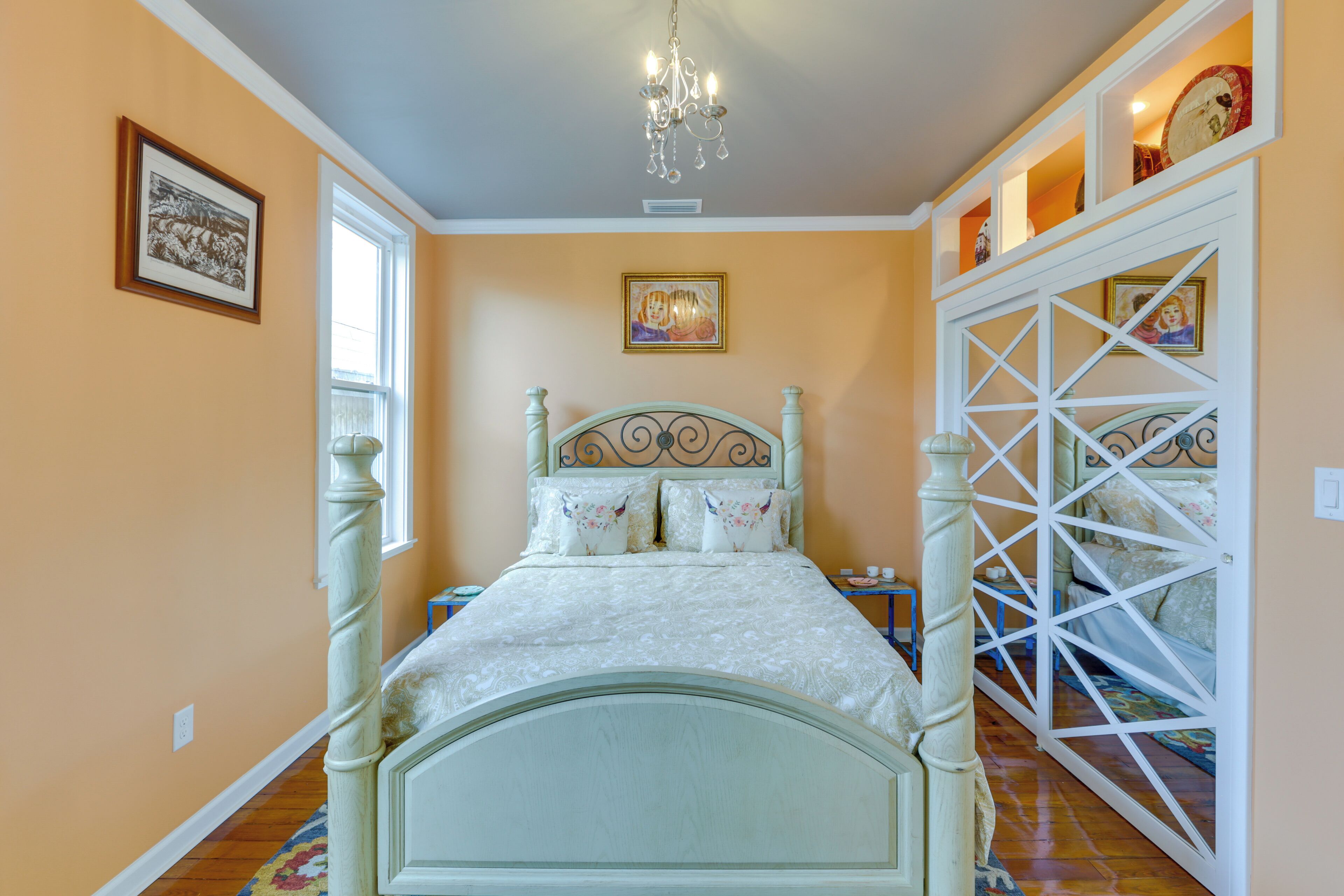 Quarto com cama de dossel, lustre e obras de arte nas paredes.
