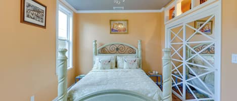 Quarto com cama de dossel, lustre e obras de arte nas paredes.