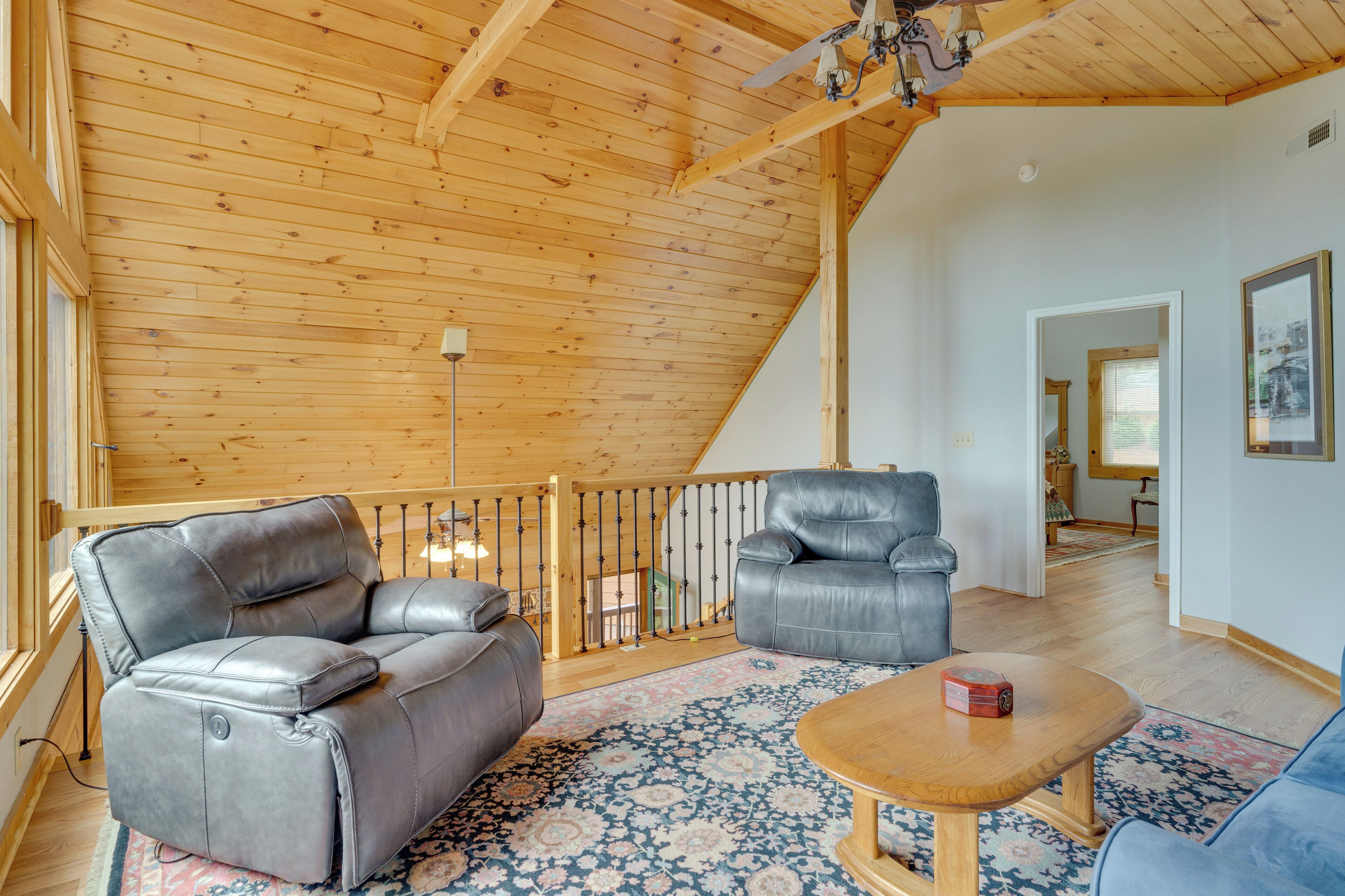 Ein geräumiges Wohnzimmer mit Holzboden, einem blauen Teppich mit Muster, einem Holztisch und zwei Ledersofas.