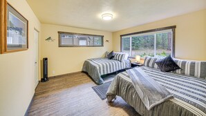 Een slaapkamer met twee bedden, een elektrische verwarming en een raam met uitzicht op bomen.