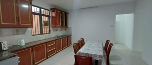 A dining area with a table and chairs, wooden cabinets, and a window with bars. - Bungalow 4 en Bord de mer Mont Choisy (Trou-aux-Biches)
