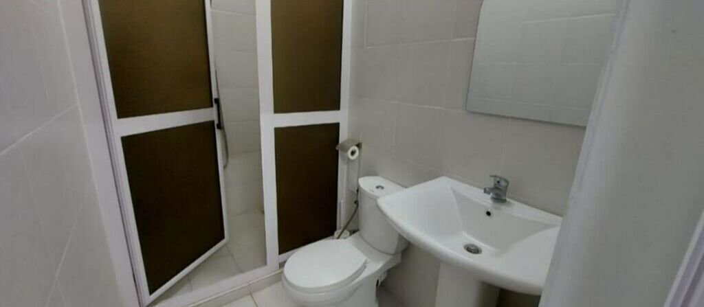 A small bathroom with a toilet, sink, and shower enclosure.
