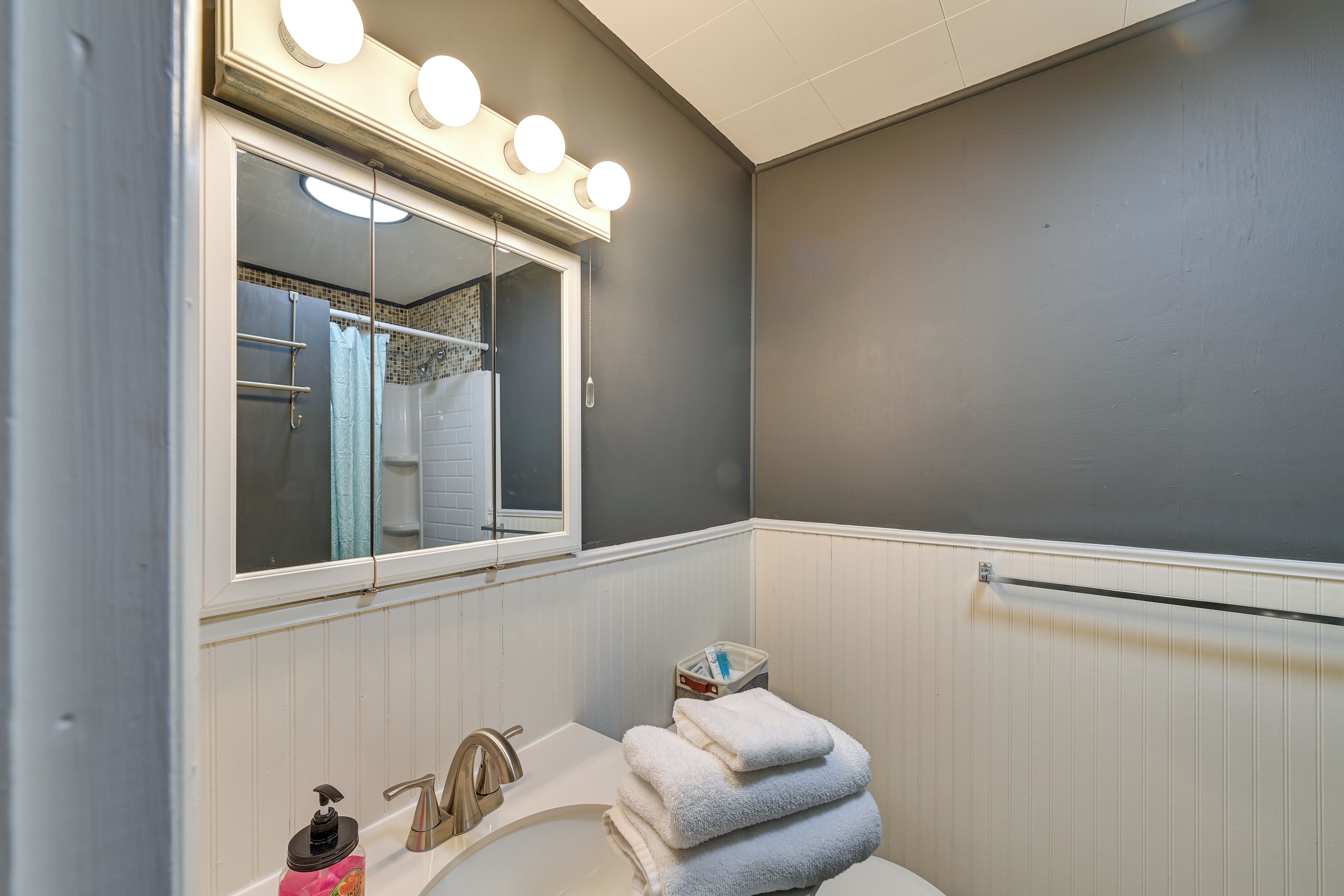 A bathroom with a vanity, a mirror with lights, a towel rack, and a window.