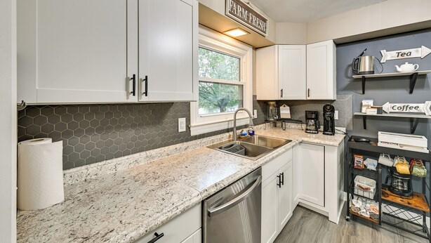 A kitchen with white cabinets, a granite countertop, a dishwasher, a coffee machine, and a shelf labeled "Tea" and "Coffee". - Dry Ridge Rental Home w/ Hot Tub & Game Room! (Crittenden)