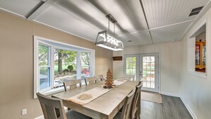 A dining area with a long table, chairs, a chandelier, and a view of the outdoors. - Dry Ridge Rental Home w/ Hot Tub & Game Room! (Crittenden)