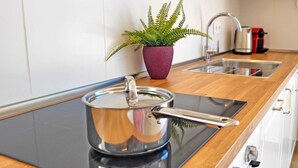 A modern kitchen with a built-in stove, a sink, and a potted plant. - Ferienwohnung Ocean Sounds A in Gran Tarajal, Innenstadt, Meerblick, Terrasse (Gran Tarajal)