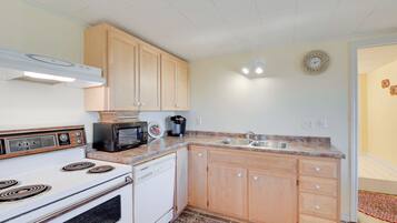 A kitchen with wooden cabinets, a white stove, a microwave, and a sink.