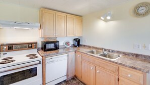 A kitchen with wooden cabinets, a microwave, a stove, a dishwasher, and a sink.