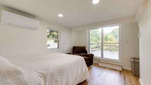 A bedroom with a large bed, a window, a chair, and a view of the outdoors. - Horseshoe Lake Vacation Rental w/ Deck & Kayaks! (Batavia)