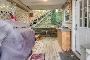 Ein überdachter Außenbereich mit Holzterrasse, einer überdachten Bank und einer Treppe zu einer Holztür.