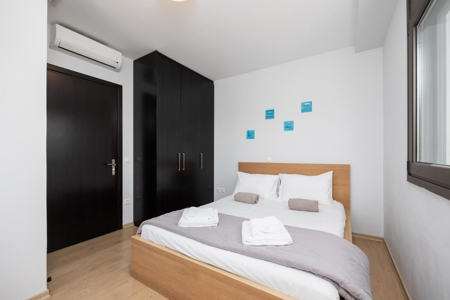 Quarto moderno com cama, guarda-roupa escuro e janela.