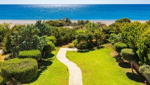 Un jardín ajardinado con un sendero serpenteante que lleva a una playa.