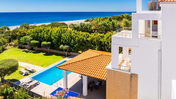 Una villa moderna con piscina, terraza amueblada al aire libre y vistas al mar.