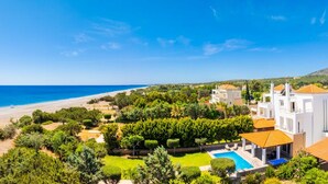 Propiedad costera con piscina, exuberante vegetación y vista al mar.