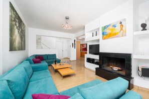 A modern living room with a sectional sofa, a fireplace, and a television.