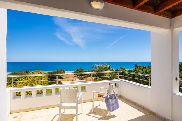 Ein Balkon mit Meerblick, ein Stuhl, ein Tisch und eine Tasche.