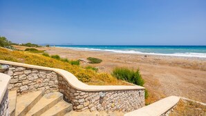 Eine Steintreppe führt zu einem Strand mit freiem Blick auf das Meer.