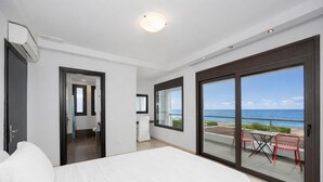 Ein Hotelzimmer mit Bett, Schreibtisch, Stuhl und einem Balkon mit Meerblick, sowie einer Schiebetür.
