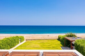 A beach view from a resort with a grassy lawn, wooden deck, and a gazebo.
