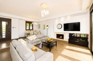 Una sala de estar con sofá, mesa de centro, televisor, chimenea y estantería.