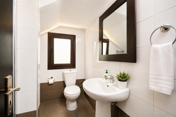 A modern bathroom with a toilet, sink, and a window above the toilet.