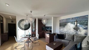 Ein modernes Wohnzimmer mit Essbereich, einer Küche und einem großen Gemälde mit Meerblick.