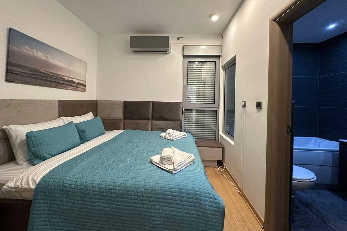 Une chambre avec un lit, une fenêtre, un appareil de climatisation et une vue sur la salle de bain.