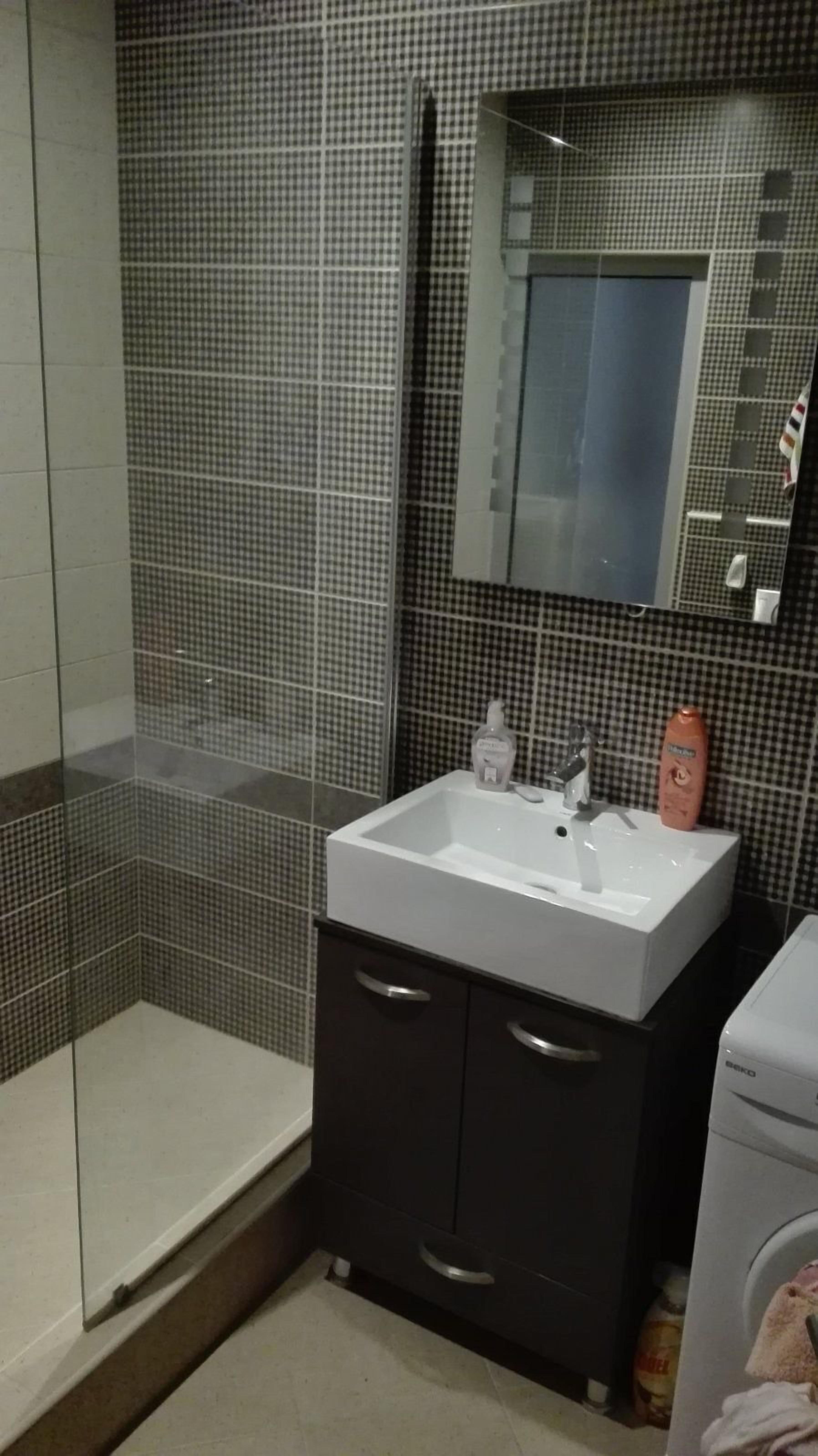 A bathroom with a white sink, dark cabinets, and a mirror above it.