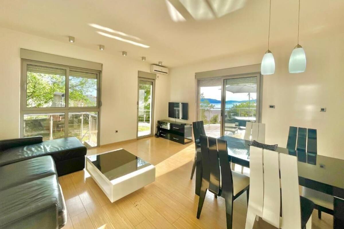 Un salon moderne comprenant un canapé, une table basse en verre, un coin repas avec des chaises et un téléviseur.