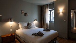 A bedroom with a bed, bedside lamps, a nightstand, a wooden dresser, a window with curtains, and a wall-mounted light fixture. - Located in Michelbach, 26 km from Mulhouse train station. (Aspach-Michelbach)