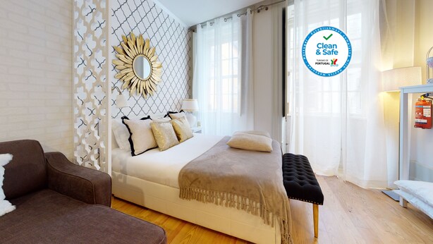 Ein modernes Hotelzimmer mit Bett, einer Wanddekoration, einer Couch und einem Nachttisch.