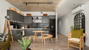 A modern kitchen with grey cabinets, a central island, and a dining area with wooden stools. - The Signature 102 (Cape Town)