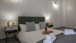 A neatly made bed with a green headboard, two bedside tables with lamps, and a tray with towels and a bottle.