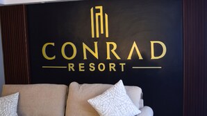 Uma parede preta com o texto "CONRAD RESORT" em letras douradas.