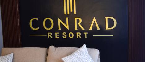 Un mur noir sur lequel on peut lire, en lettres dorées, le texte « CONRAD RESORT ».