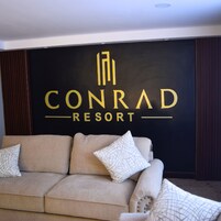 A black wall with the text "CONRAD RESORT" in gold letters.
