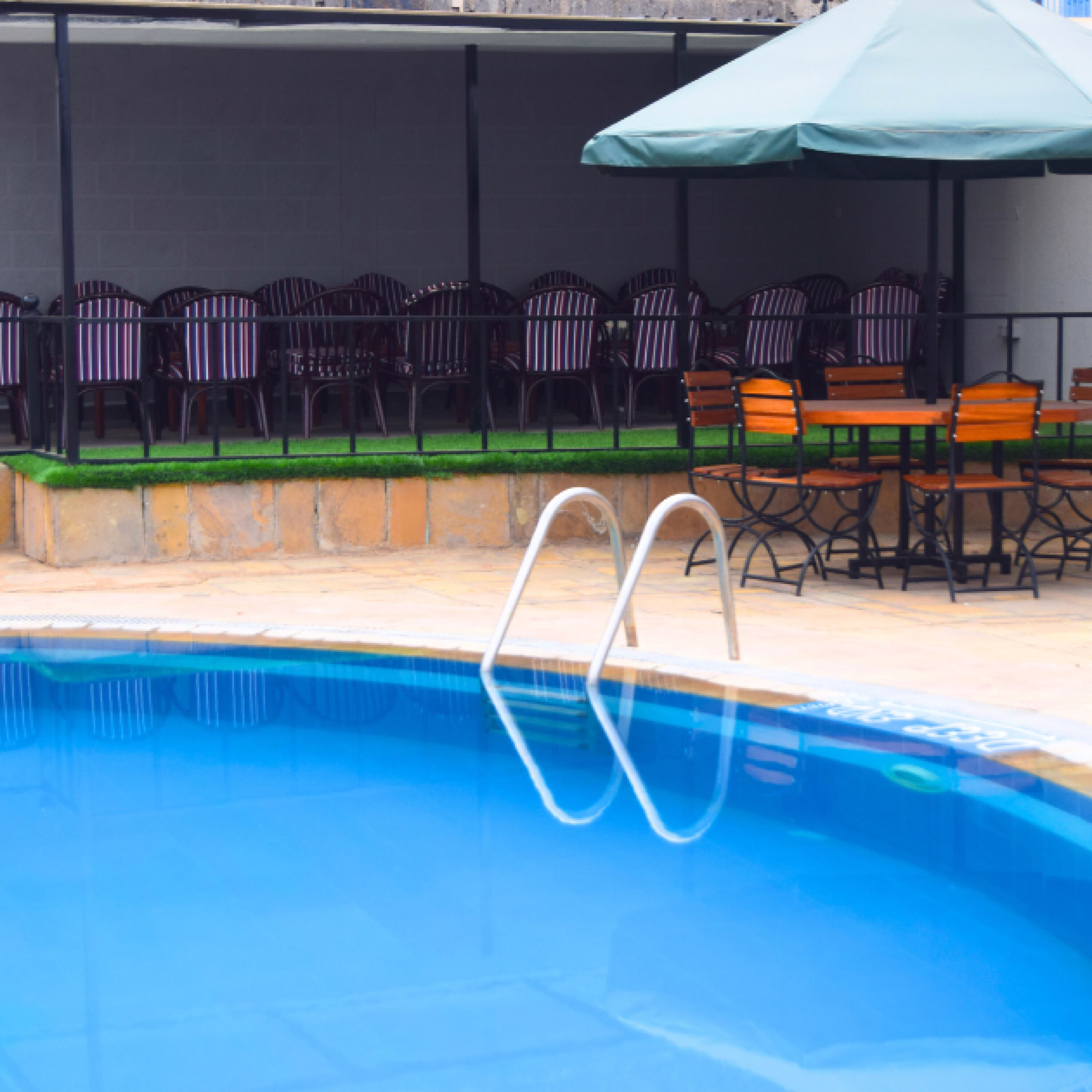 Piscina con tabla de salto, rodeada de mobiliario exterior con sillas y mesas.