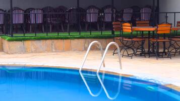 Piscina con tabla de salto, rodeada de mobiliario exterior con sillas y mesas.