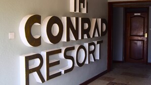 Parede com o texto "The Conrad Resort" em letras grandes e negrito.