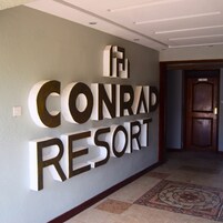 A wall with the text "The Conrad Resort" in large, bold letters.
