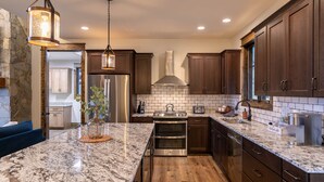 A modern kitchen with granite countertops, stainless steel appliances, and wooden cabinets. - Timberline at Eagles Nest - Village with Views! (Banner Elk)